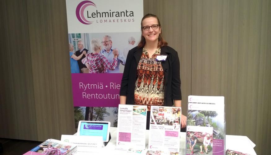 Nainen Lehmirannan lomakeskuksen esittelypöydän takana hymyillen
